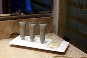 Una encimera de baño con tres productos para el cuidado de la piel y una pastilla de jabón.