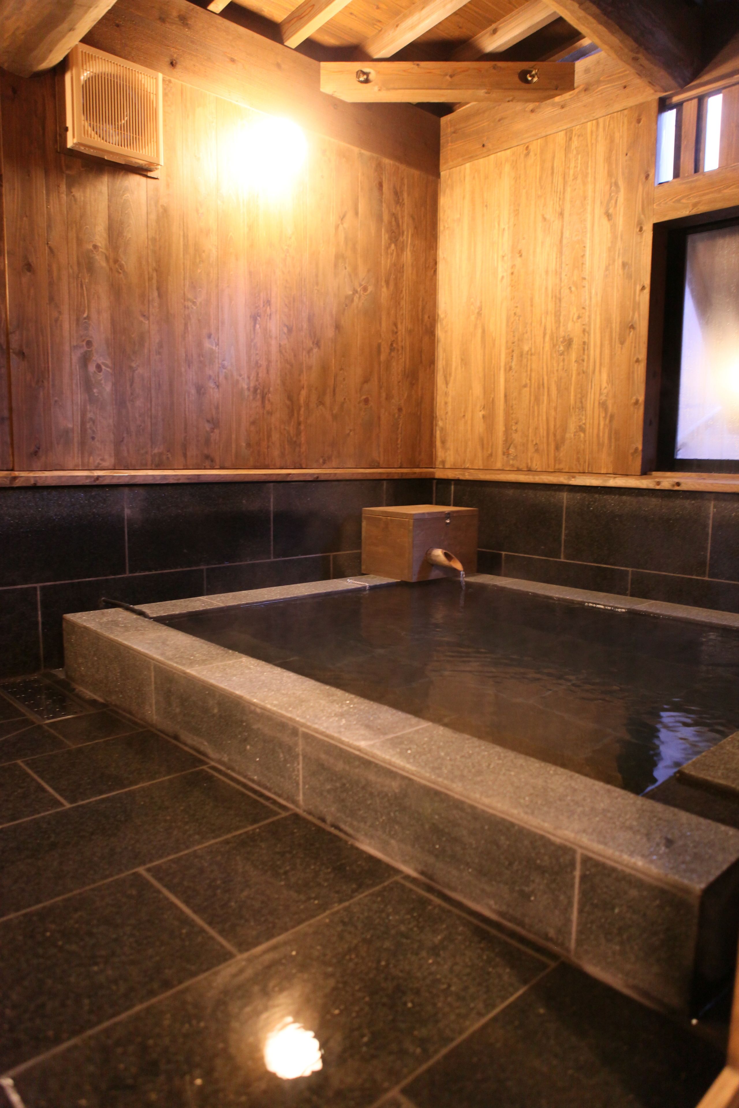 Un intérieur en bois avec un bain à remous dont le fond est recouvert de pierres.