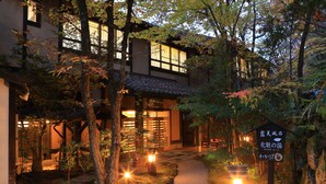 A traditional Japanese building with a pathway leading to the entrance, surrounded by trees and illuminated by warm lighting. - Kurokawa Onsen Ryokan Wakaba (Minamioguni)
