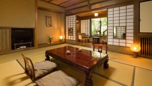 A traditional Japanese room with tatami flooring, a low wooden table, a television, and sliding doors. - Kurokawa Onsen Ryokan Wakaba (Minamioguni)