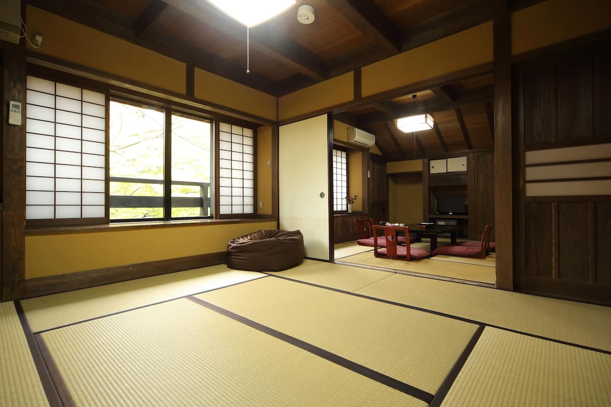 A traditional Japanese room with tatami flooring, a sliding door, and a dining area with a table and chairs.
