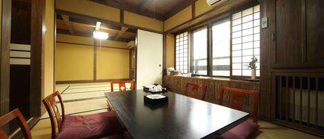 A traditional Japanese room with tatami flooring, a low table, wooden chairs, and sliding doors.