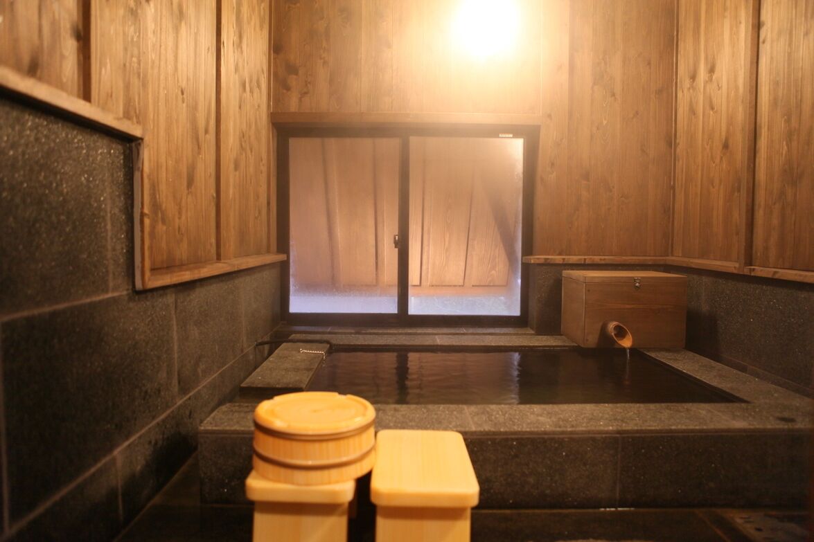 Un onsen japonais traditionnel, avec des murs en bois, un sol en pierre et un banc en bois.