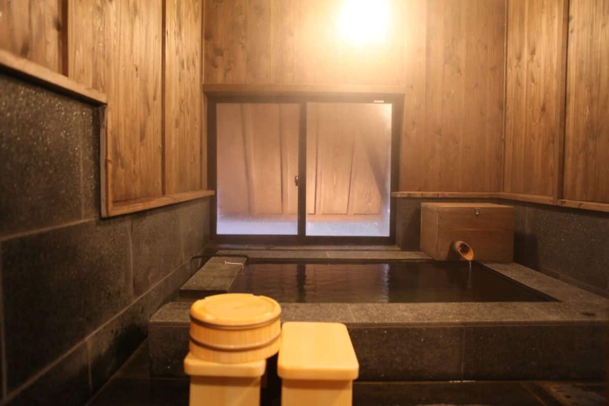 Un onsen japonais traditionnel, avec des murs en bois, un sol en pierre et un banc en bois.