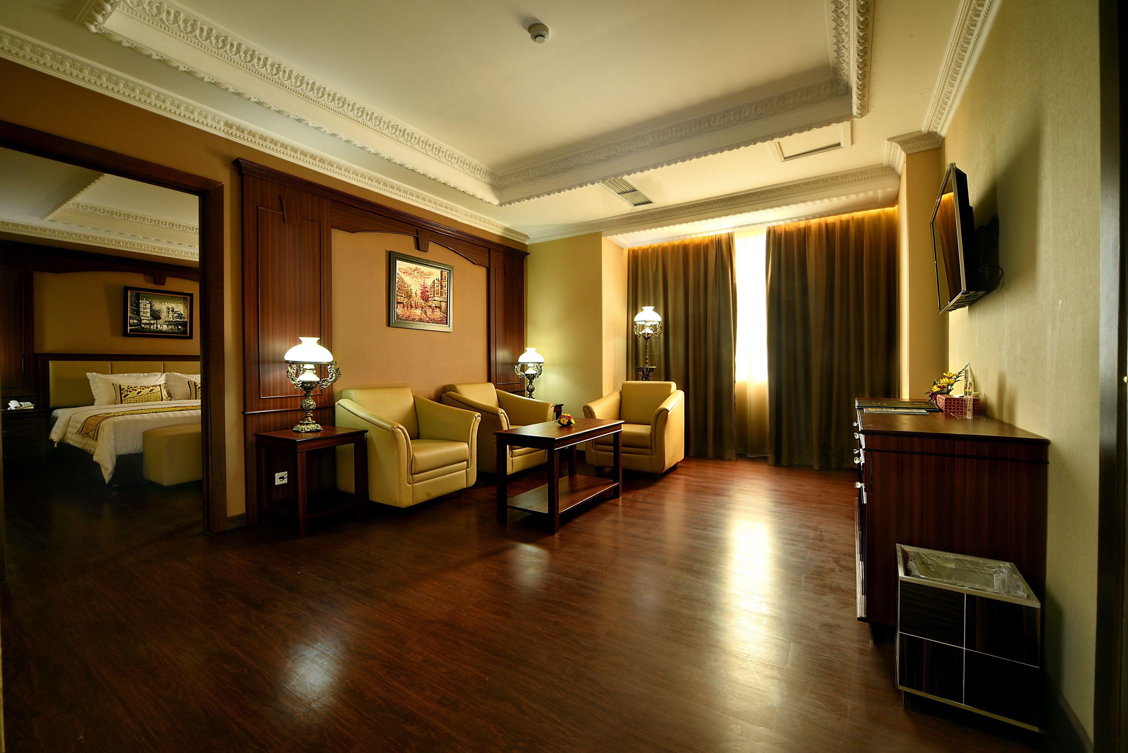A hotel room with a bed, two armchairs, a coffee table, a TV, and a wooden cabinet.