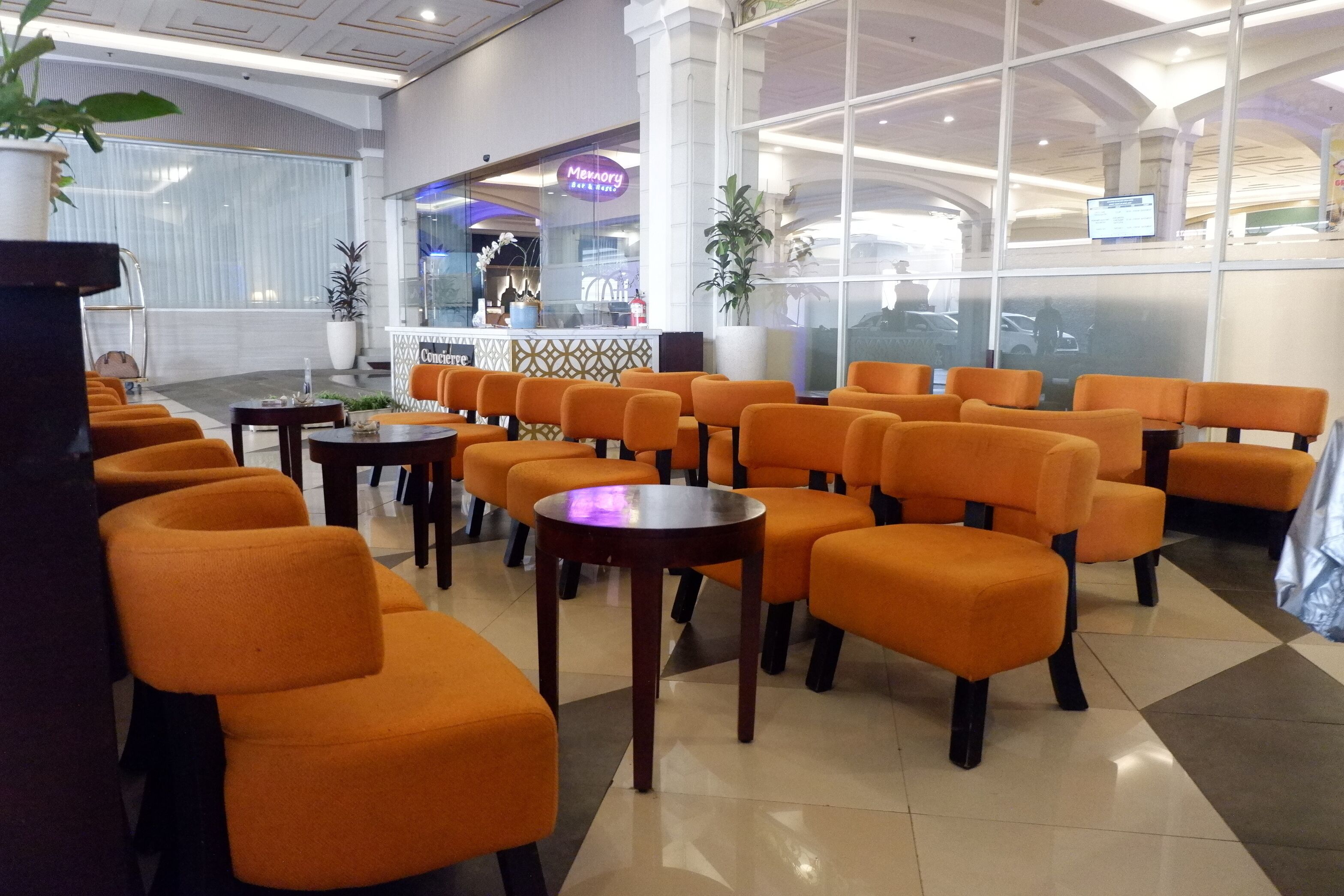 A hotel lobby with orange seating, a reception area, and a view of the parking area.