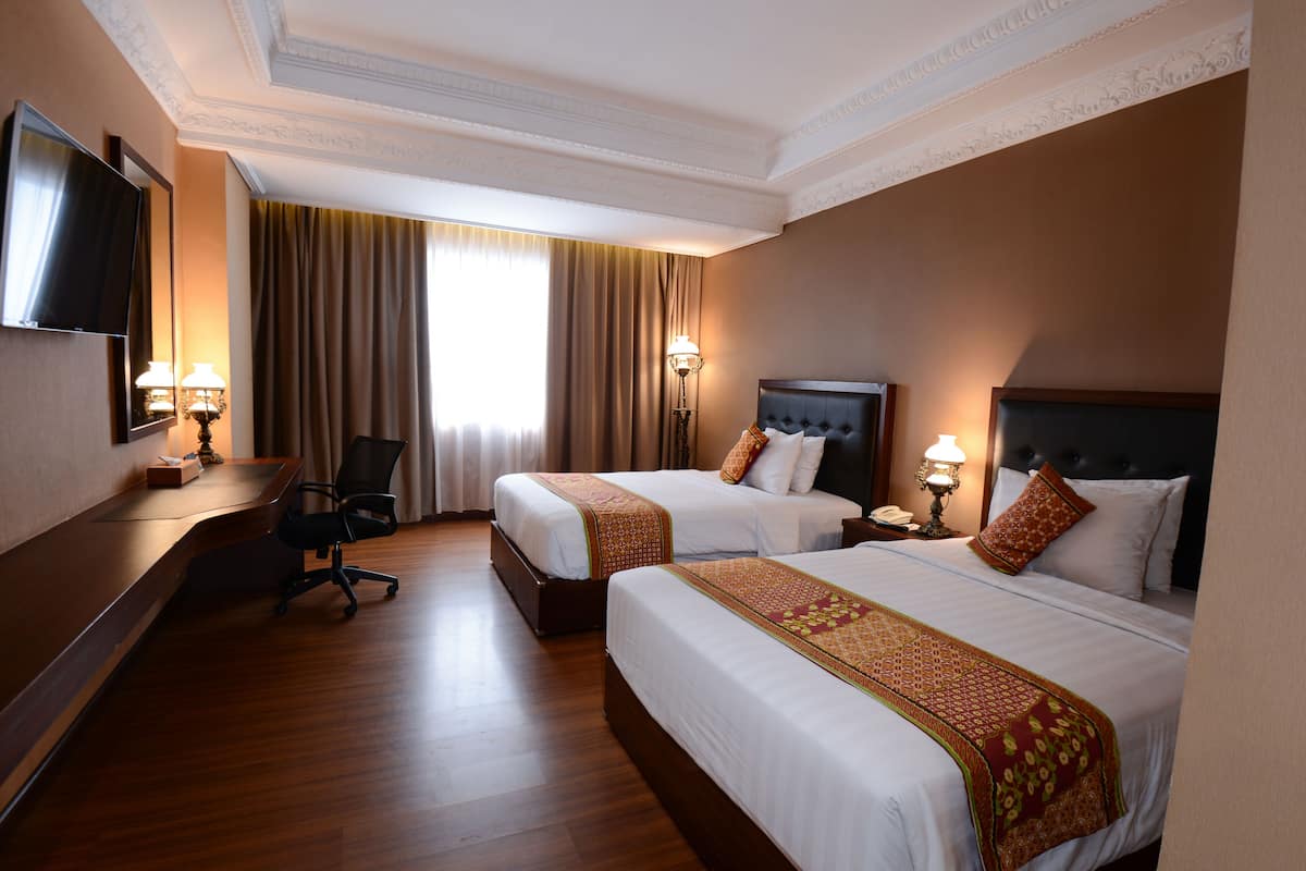 Una habitación de hotel con dos camas, un escritorio, una silla y un televisor.