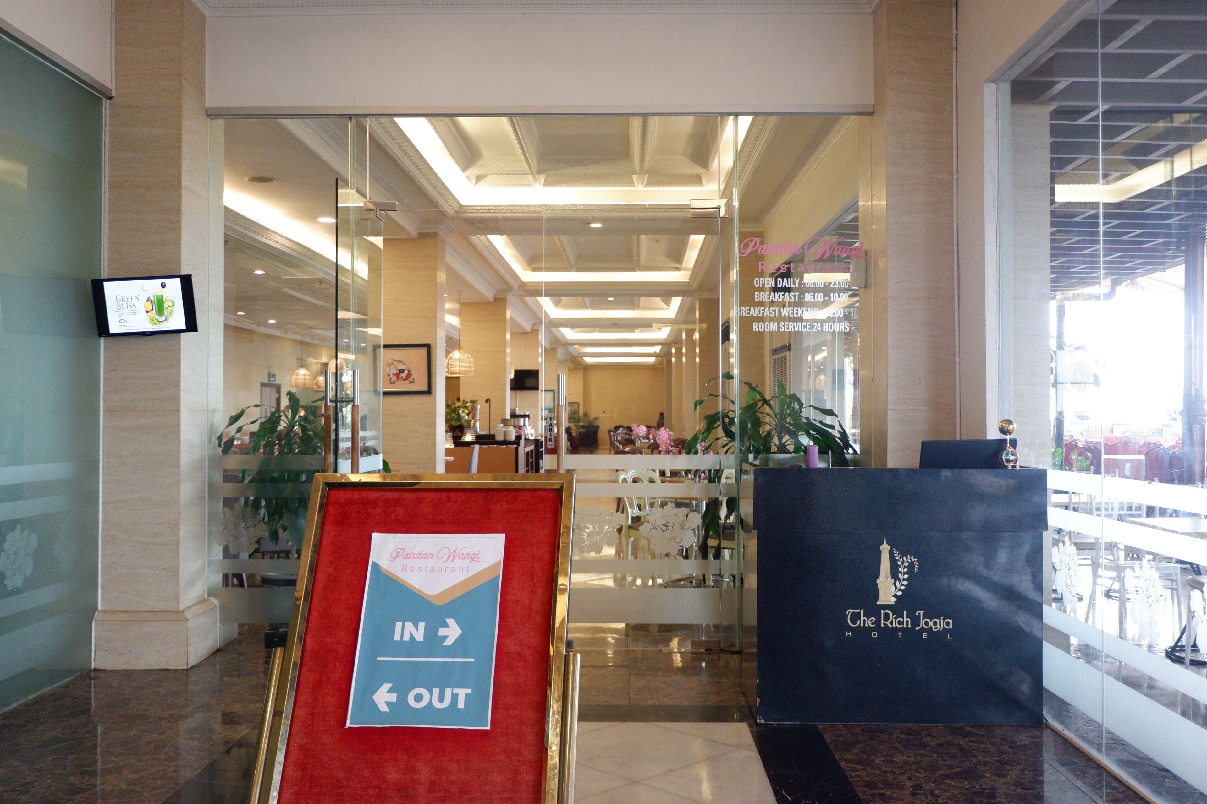 Een hotel lobby met een receptiebalie, bewegwijzering en uitzicht op het restaurantgedeelte.