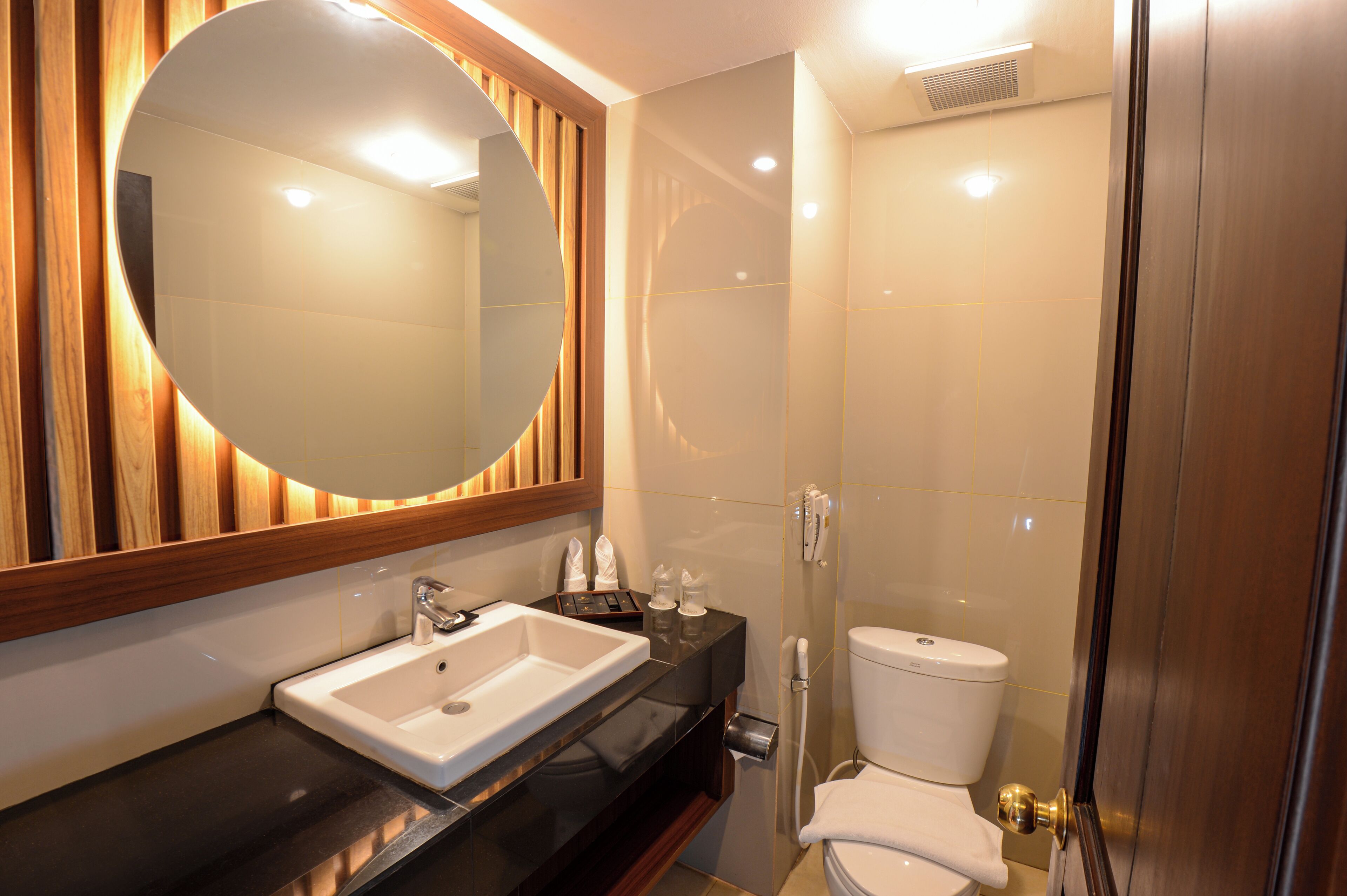 Une salle de bain moderne avec un miroir rond, un lavabo et des toilettes.