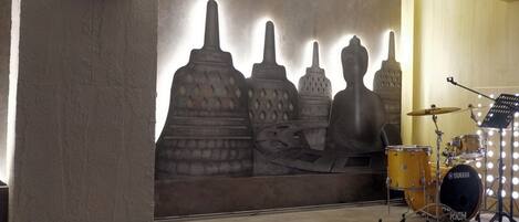 A drum set with a Yamaha logo, a wall with abstract sculptures, and a light fixture.