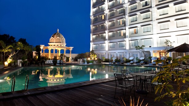 Un hotel con una piscina grande, un edificio en forma de cúpula y una estructura de varios pisos con balcones.