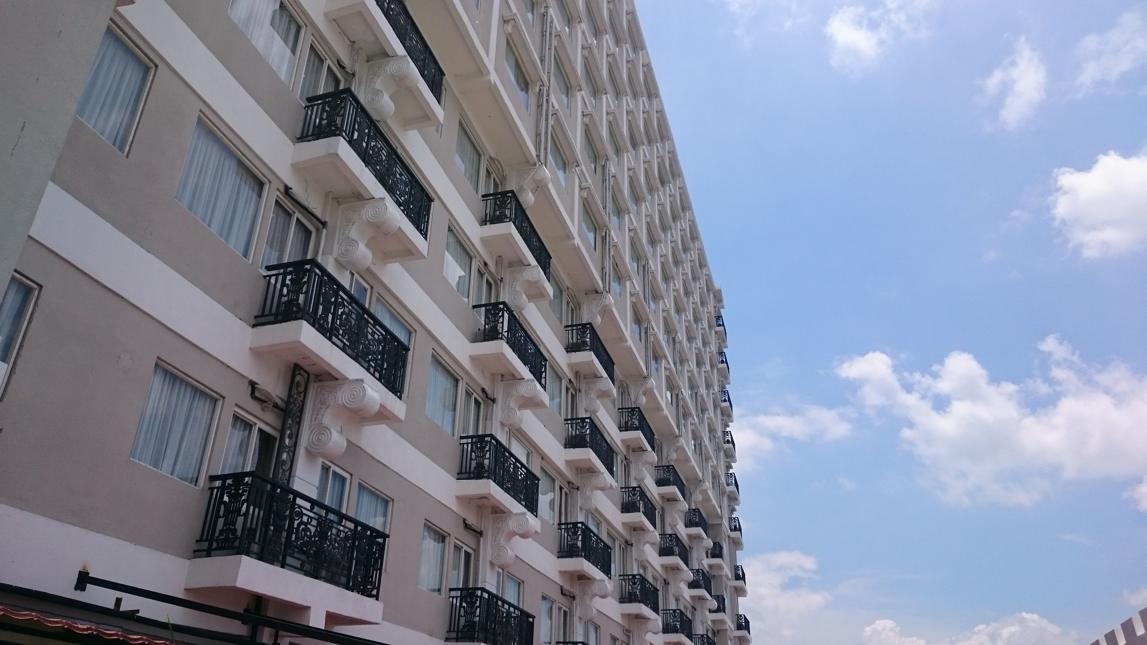 A multi-story hotel with balconies, large windows, and a clear sky.