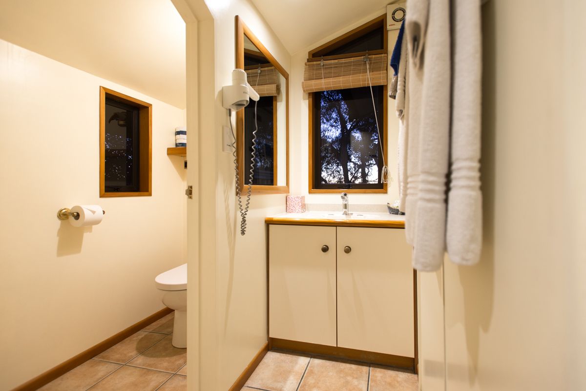 Ein Badezimmer mit Toilette, einem Spiegelschrank, einem Fenster mit Jalousien und einem Handtuchhalter.
