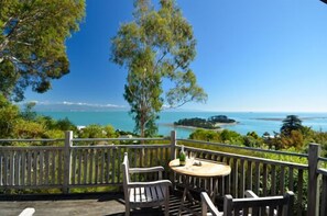 A wooden deck with a table and chairs overlooking a coastal view.