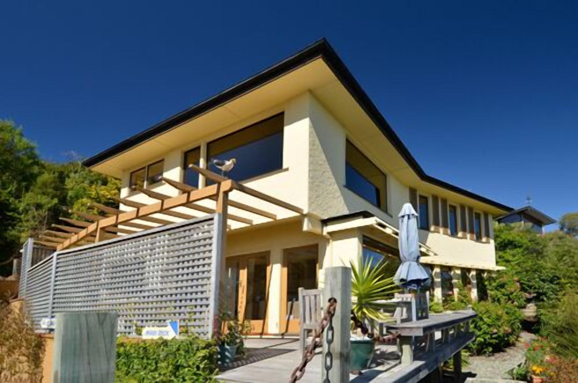A modern two-story house with a covered patio and a garden.