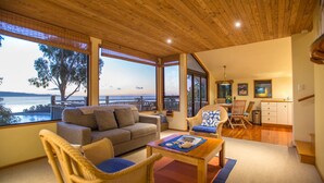 A spacious living area with a large window overlooking a scenic view, a cozy seating arrangement, and a wooden ceiling. - The Wheelhouse Inn (Nelson)