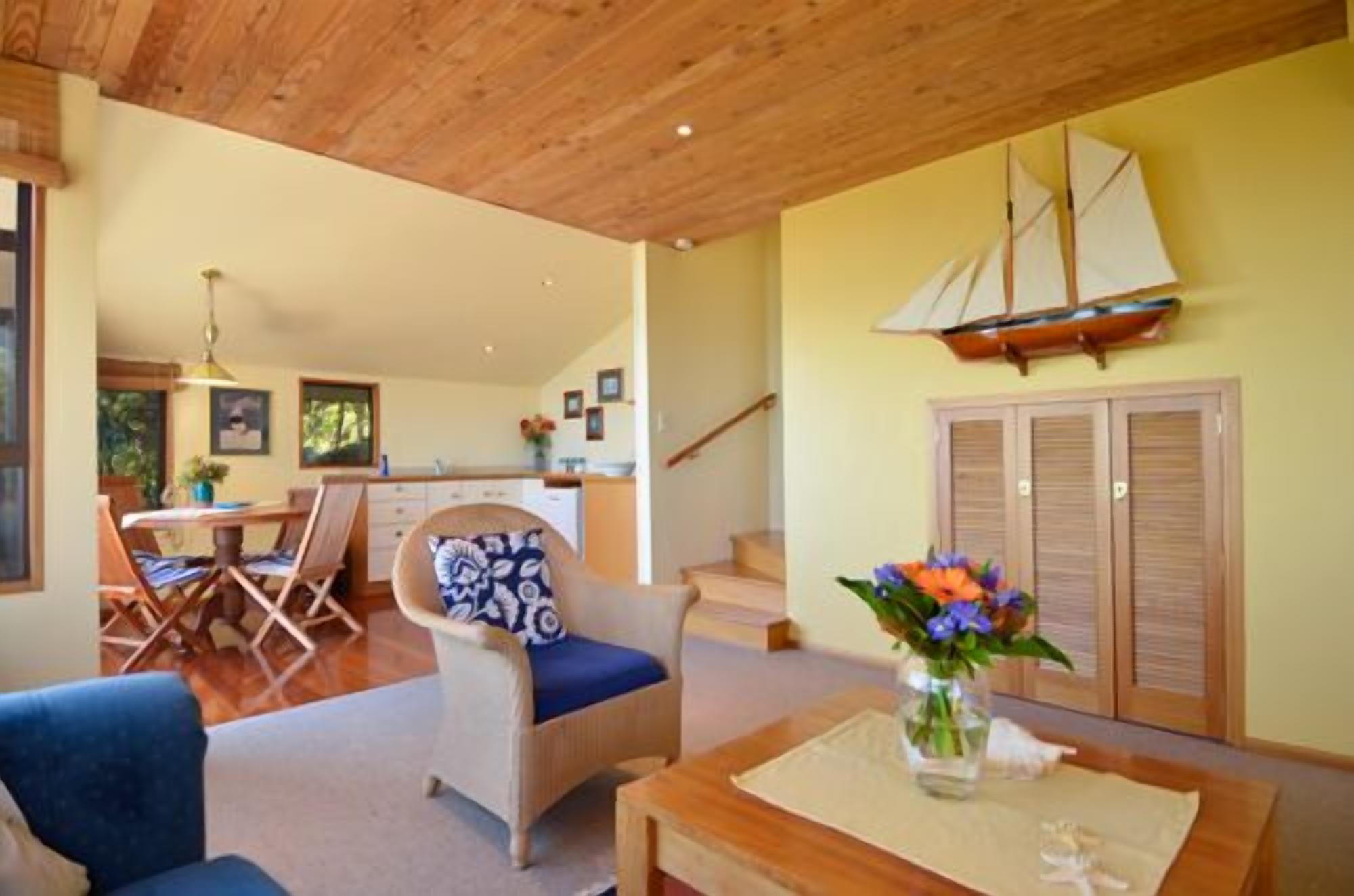A spacious living area with a wooden ceiling, a dining area with a table and chairs, and a staircase leading to another level.