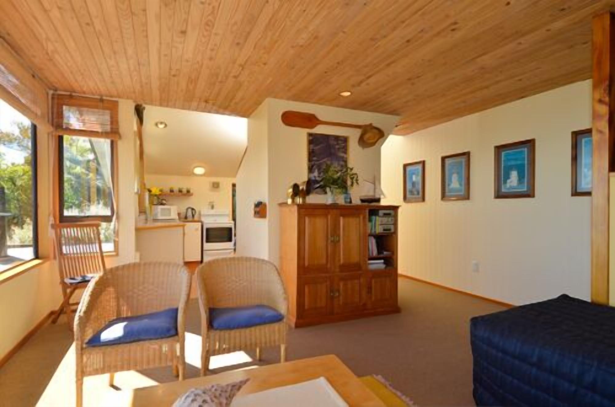 A cozy living room with wicker chairs, a wooden cabinet, and a dining table.