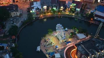 An aerial view of a waterfront amusement park with a Ferris wheel and various rides.