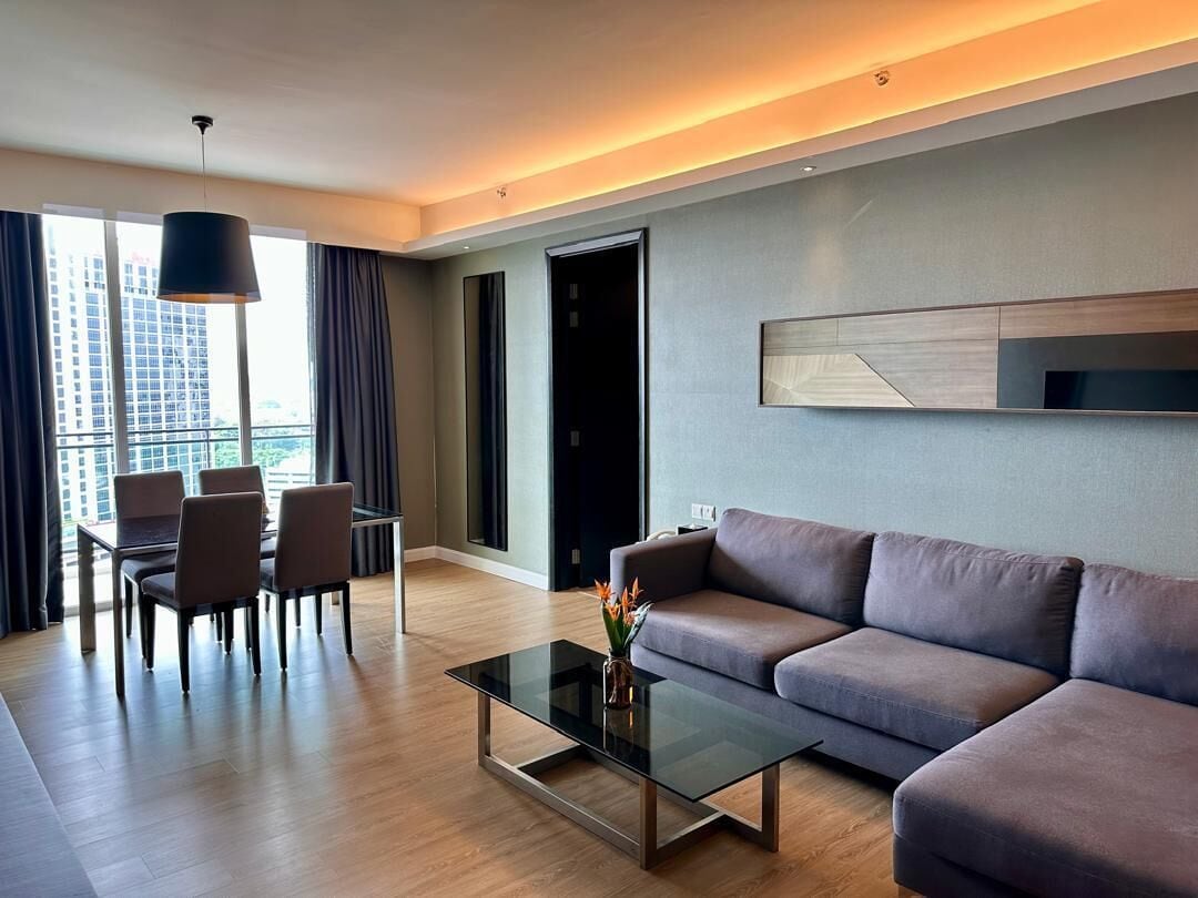 Un salon moderne avec un canapé, une table basse en verre et un coin repas avec des chaises.