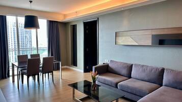 A modern living room with a sofa, a glass coffee table, and a dining area with chairs.