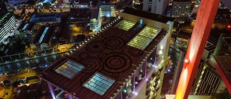 Un edificio de gran altura con jardín en la azotea y señalización iluminada.