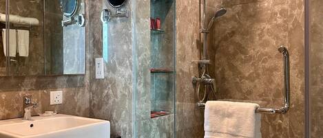 A modern bathroom with a glass-enclosed shower, a white sink, and a mirror.