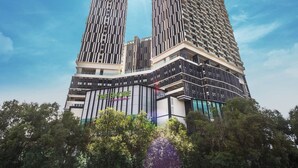 Un edificio de gran altura con un diseño vertical llamativo, múltiples balcones y un cielo despejado.