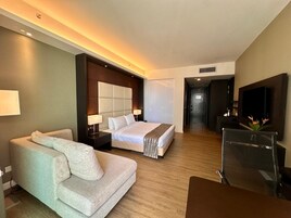 Ein Hotelzimmer mit einem Bett, einer Couch, einem Fernseher und einem Schreibtisch.