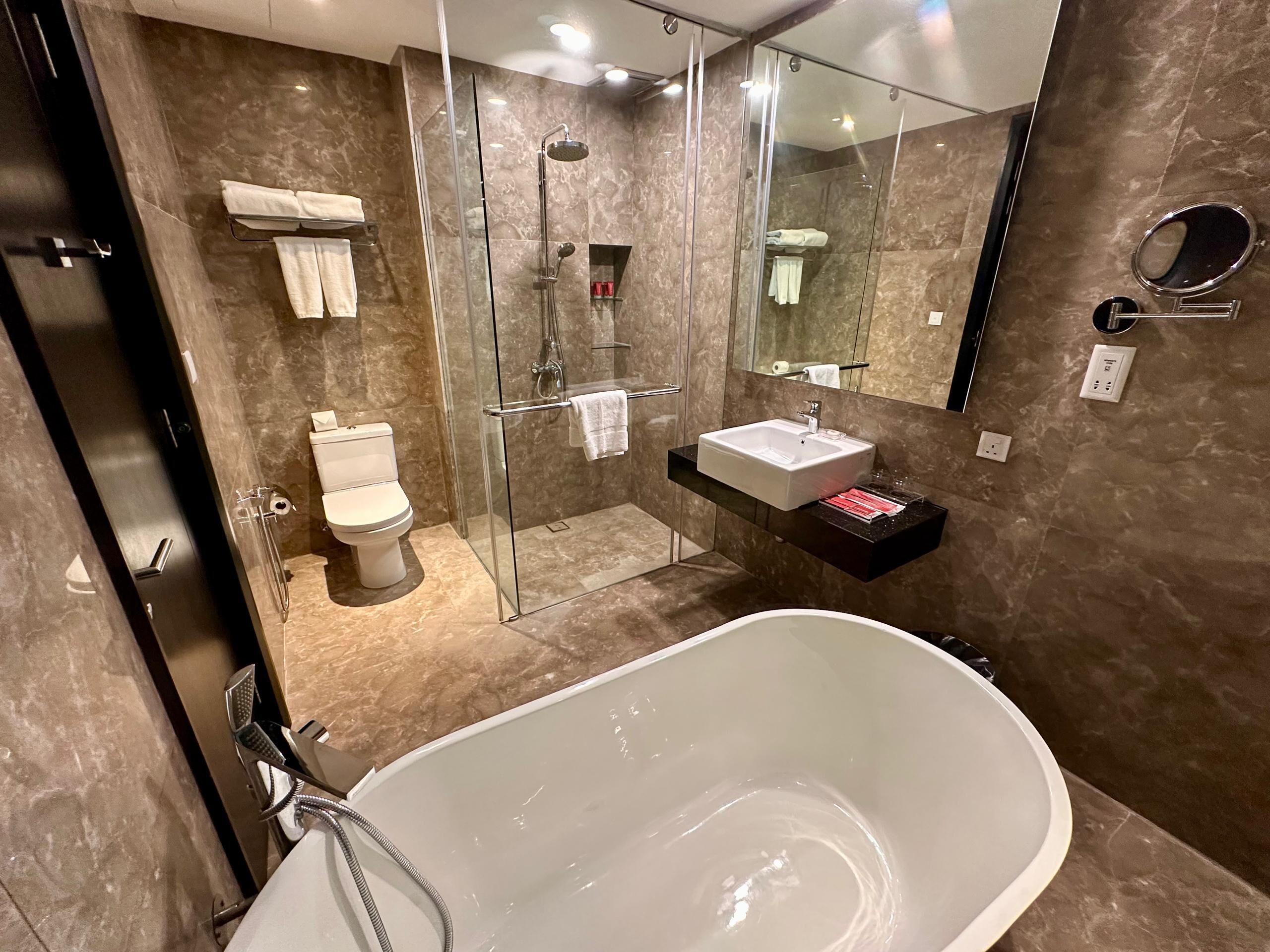 A modern bathroom with a glass-enclosed shower, a freestanding bathtub, and a vanity with a sink.