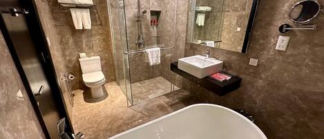 Un baño moderno con ducha envuelta en vidrio, una bañera independiente y un tocador con lavabo.