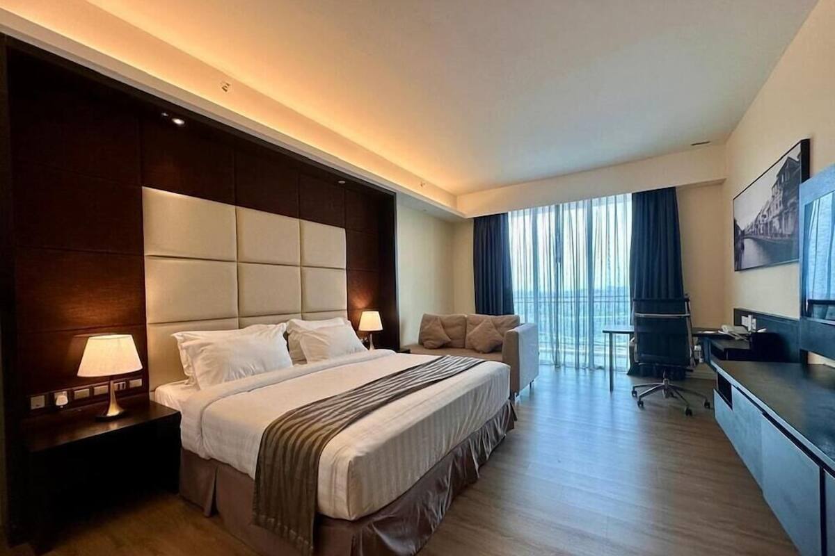 Habitación de hotel moderna con una cama grande, un escritorio y vistas a la ciudad.