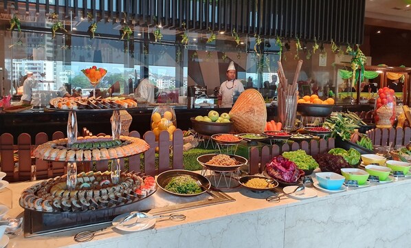 A buffet with various food items, including sushi, fruits, and vegetables.