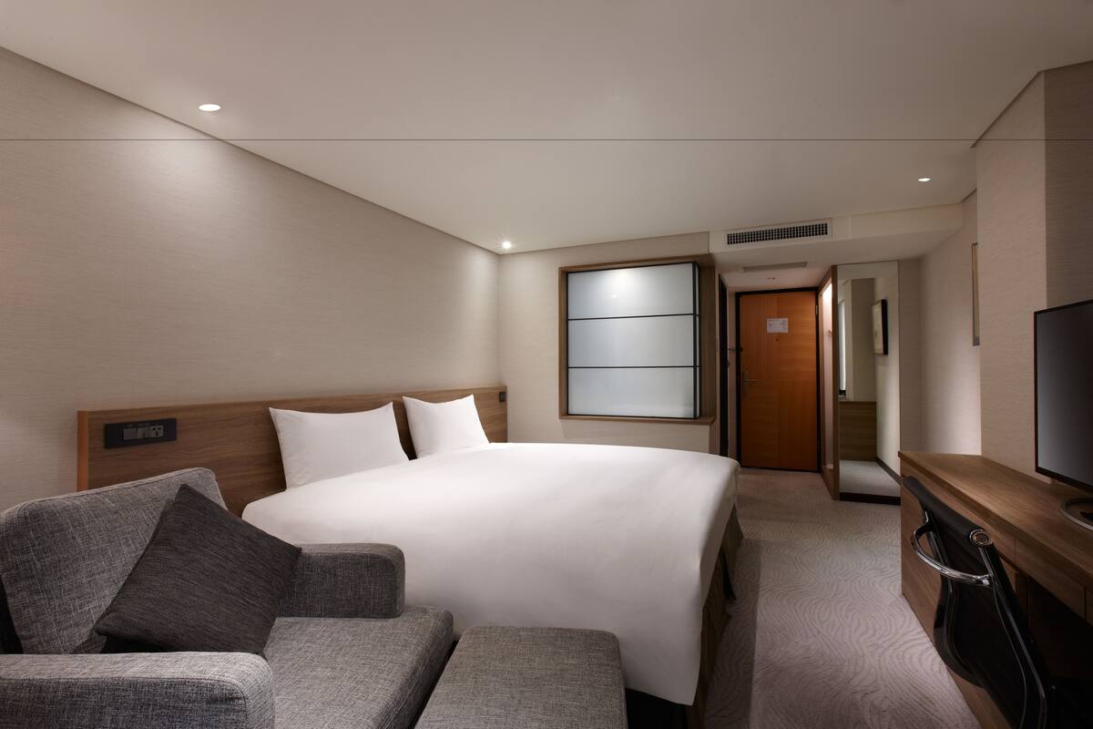 Et moderne hotelværelse med en stor seng, en sofa, et fjernsyn og et træskrivebord.