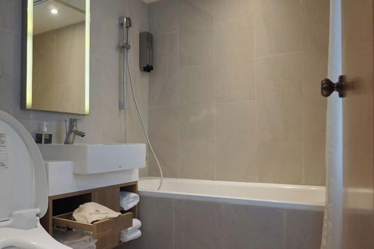 A modern bathroom with a bathtub, a toilet, a sink, and a mirror.