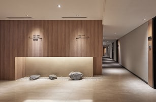 Een moderne hotelgang met houten paneelwanden, richtingsborden en een minimalistisch design.