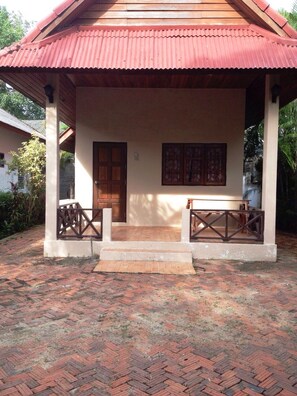 A covered outdoor area with a wooden bench, a door, and a wall-mounted picture. - Baan Rim Lay Lipa Noi (Koh Samui)