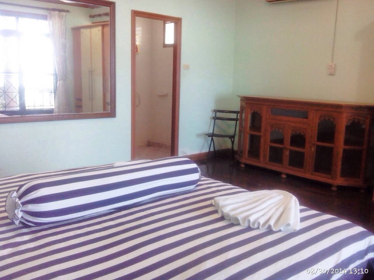 A bedroom with a bed, a wooden cabinet, and a mirror on the wall.