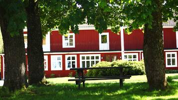 A red building with white trim, a bench, and trees in a grassy area.