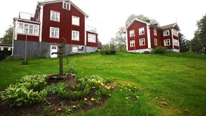 A red two-story house with a well-maintained lawn and garden. - Nyhyttans Kurort (Nora)