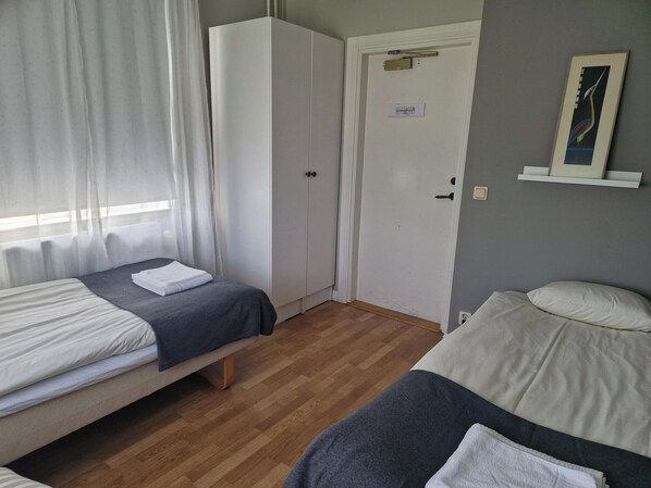 A room with two beds, a wardrobe, a door with a nameplate, and a wall-mounted shelf with a picture. - Nyhyttans Kurort (Nora)