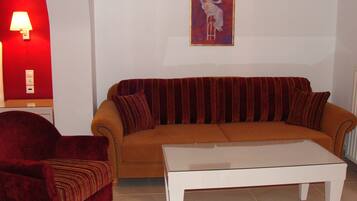 Una sala de estar con sofá, sillón y una mesa de centro blanca.