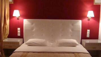 A hotel room with a large bed, two bedside lamps, and a red accent wall.