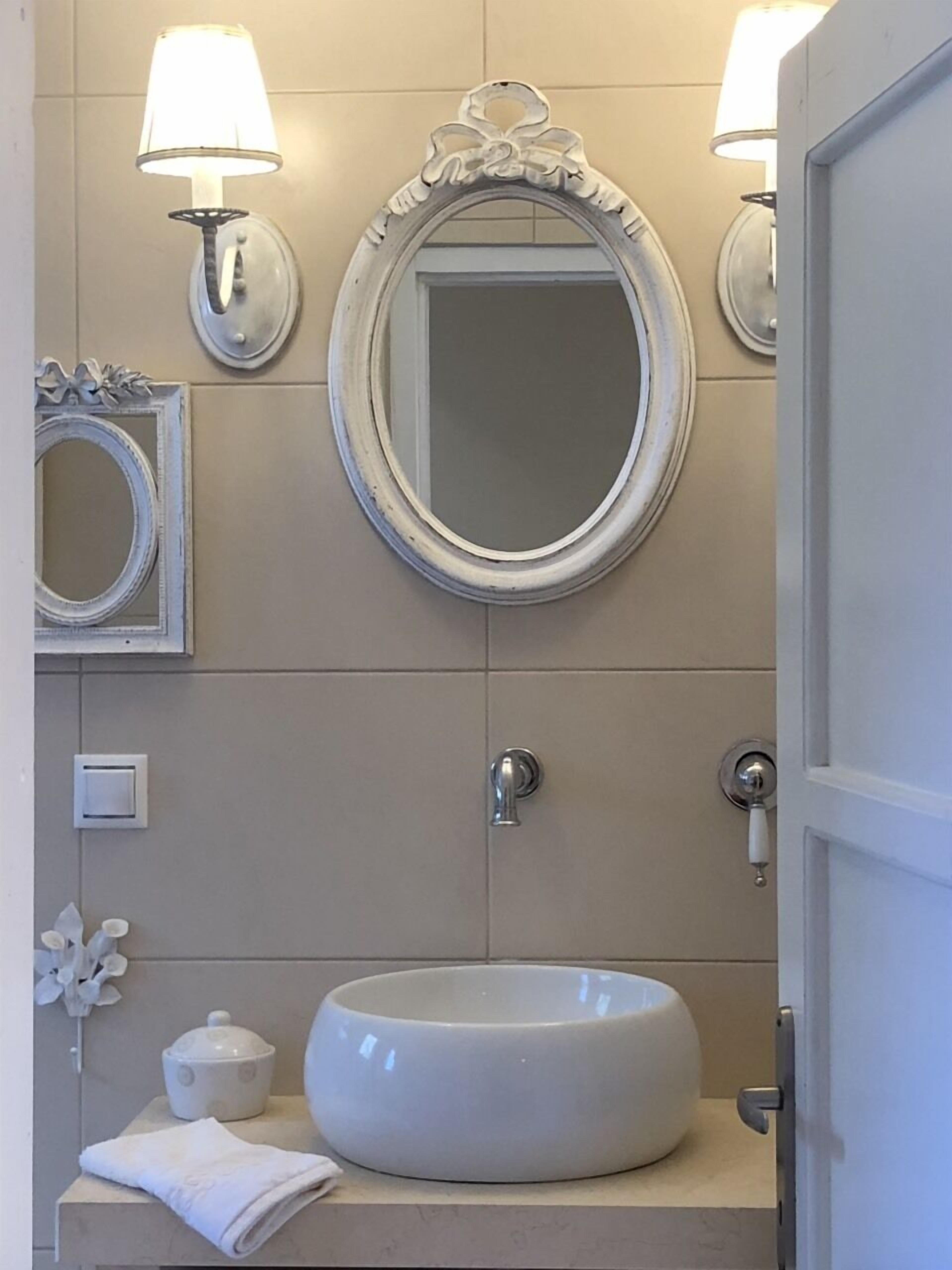 A bathroom with a round sink, two wall-mounted lights, a mirror, and a door.