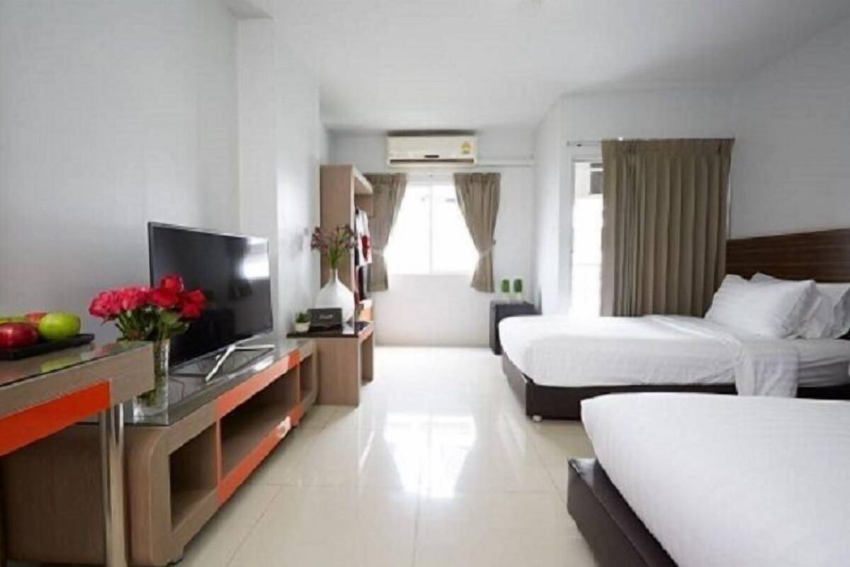 Une chambre d’hôtel avec deux lits, une télévision, un bureau avec un ordinateur et une fenêtre avec des rideaux.