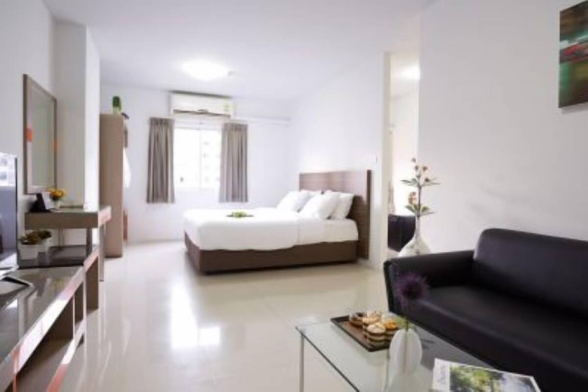 Une chambre d’hôtel moderne équipée d’un lit, d’un canapé, d’une table basse en verre et d’un téléviseur.