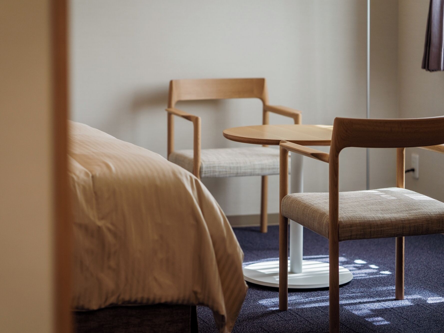 Une chambre d’hôtel avec un lit, une table ronde et deux chaises.