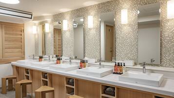 A modern bathroom with two sinks, wooden cabinets, and a tiled backsplash.