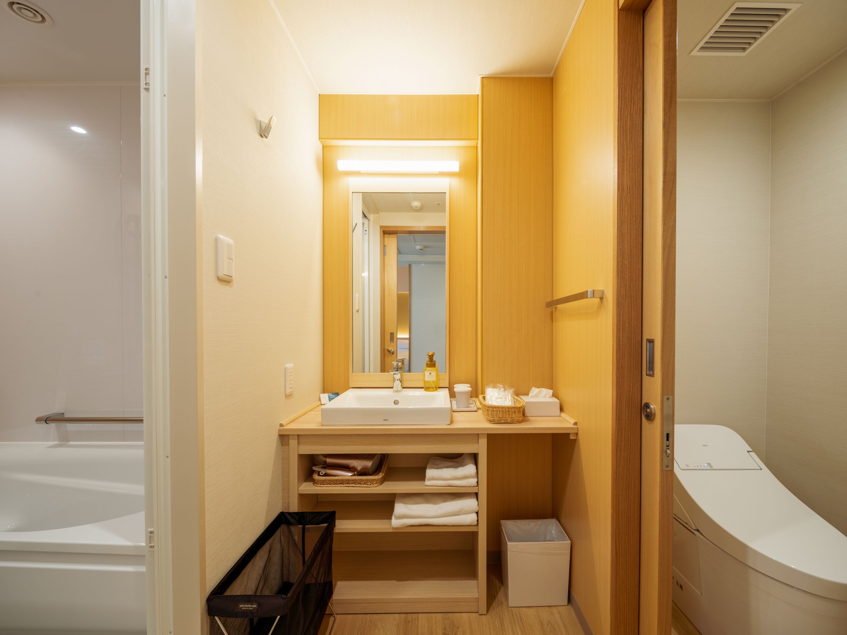 A compact bathroom with a sink, mirror, and a toilet.