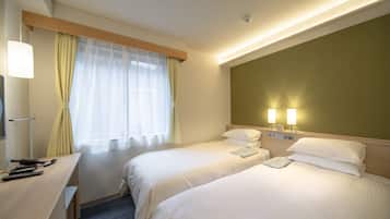 A hotel room with two beds, a desk, and a window with curtains.